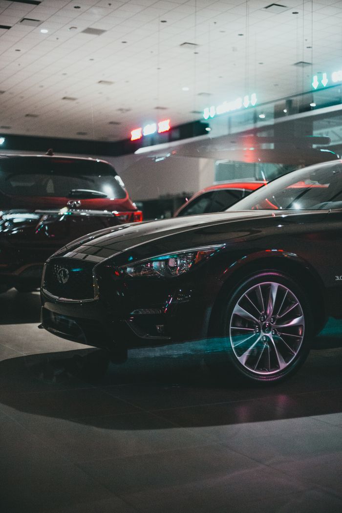 About Modern polish expensive automobiles of black color placed on asphalt illuminated parking lots